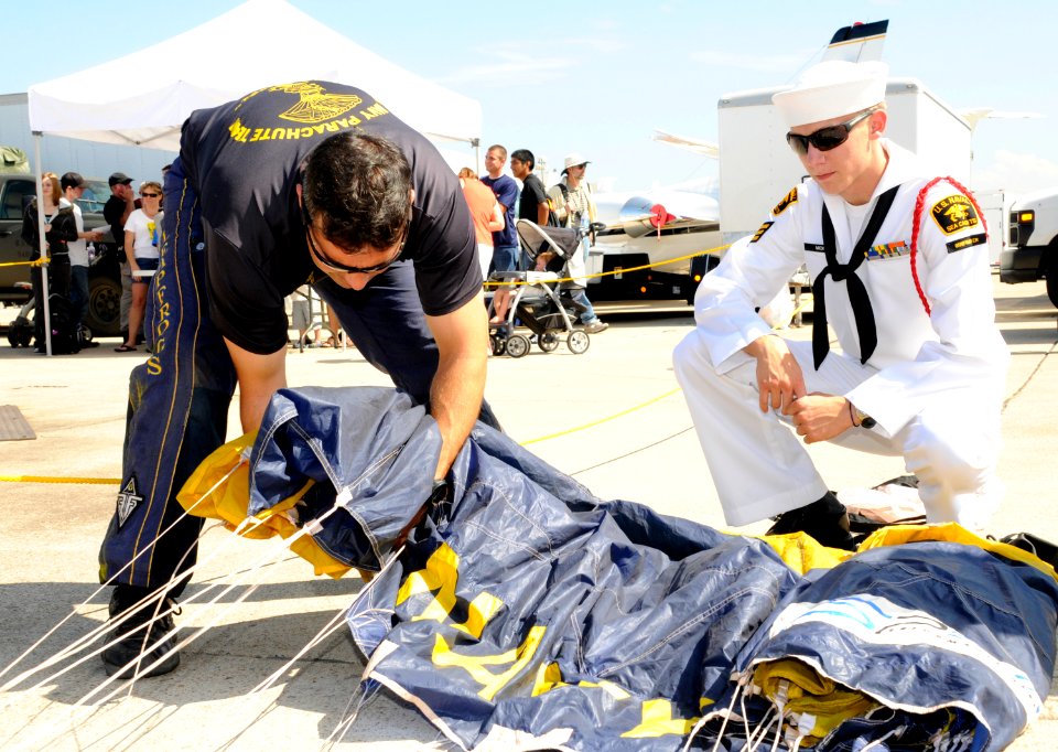 US Navy 101002-N-5366K-167 Special Warfare Operator 1st Class (SEAL) Aaron Darakjy shows a sea cadet how to pack his parachute after performing dur