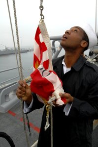 US Navy 101013-N-6477M-275 Seaman Mario Curtis prepares to raise the Navy Jack for morning colors aboard the amphibious transport dock ship USS Cle