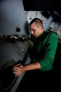 US Navy 101011-N-3793B-041 Aviation Machinist's Mate 3rd Class Robert Leggett installs a pre-check valve in an F-A-18C Hornet aboard the aircraft c