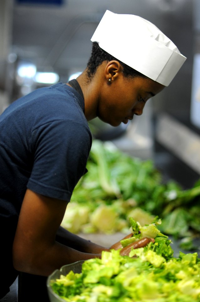US Navy 101012-N-3793B-178 Culinary Specialist Seaman Christine Mumphrey, from Phoenix, Ariz., prepares lettuce for the salad bar on the mess decks