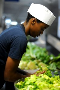 US Navy 101012-N-3793B-178 Culinary Specialist Seaman Christine Mumphrey, from Phoenix, Ariz., prepares lettuce for the salad bar on the mess decks photo