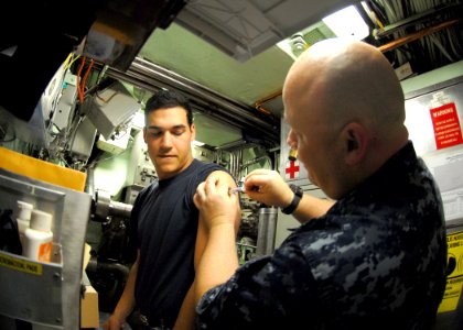 US Navy 101013-N-7705S-031 Chief Hospital Corpsman Dale Lyons administers the annual influenza vaccination to Electronics Technician Seaman Thomas photo