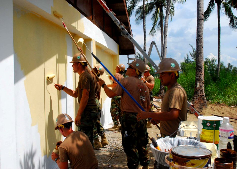 US Navy 101015-N-3589B-185 eabees assigned to Naval Mobile Construction Battalion (NMCB) 11 paint the exterior walls of a schoolhouse they built wi