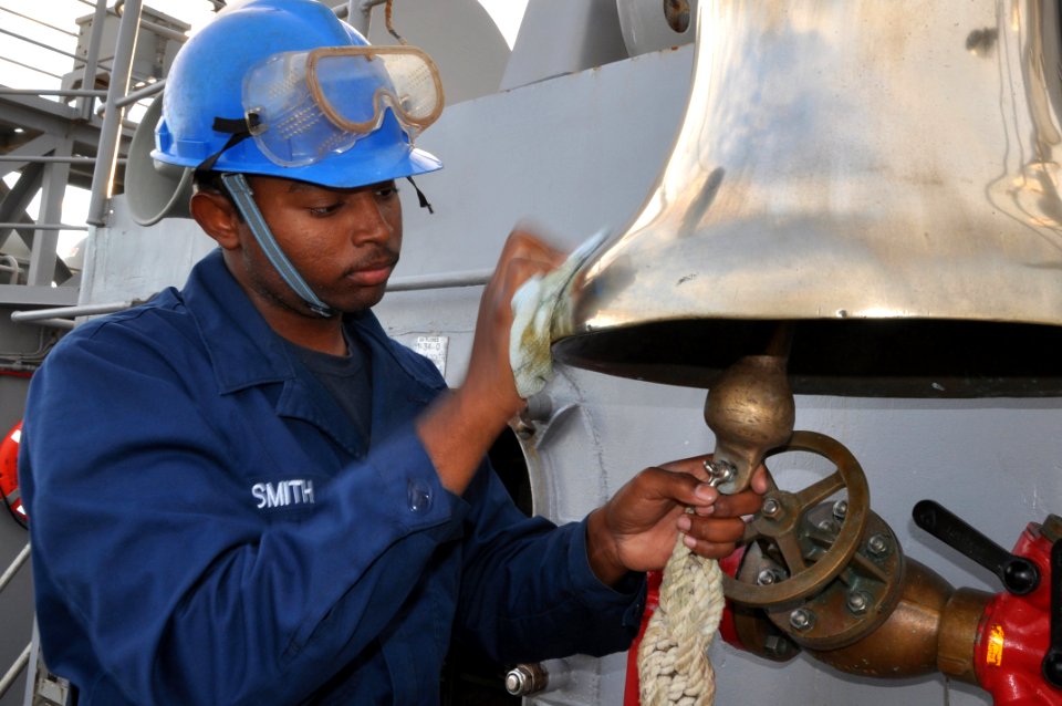 US Navy 111128-N-YX169-054 Seaman Davion Smith polishes the ship's bell on the forecastle of the amphibious transport dock ship USS Ponce (LPD 15)