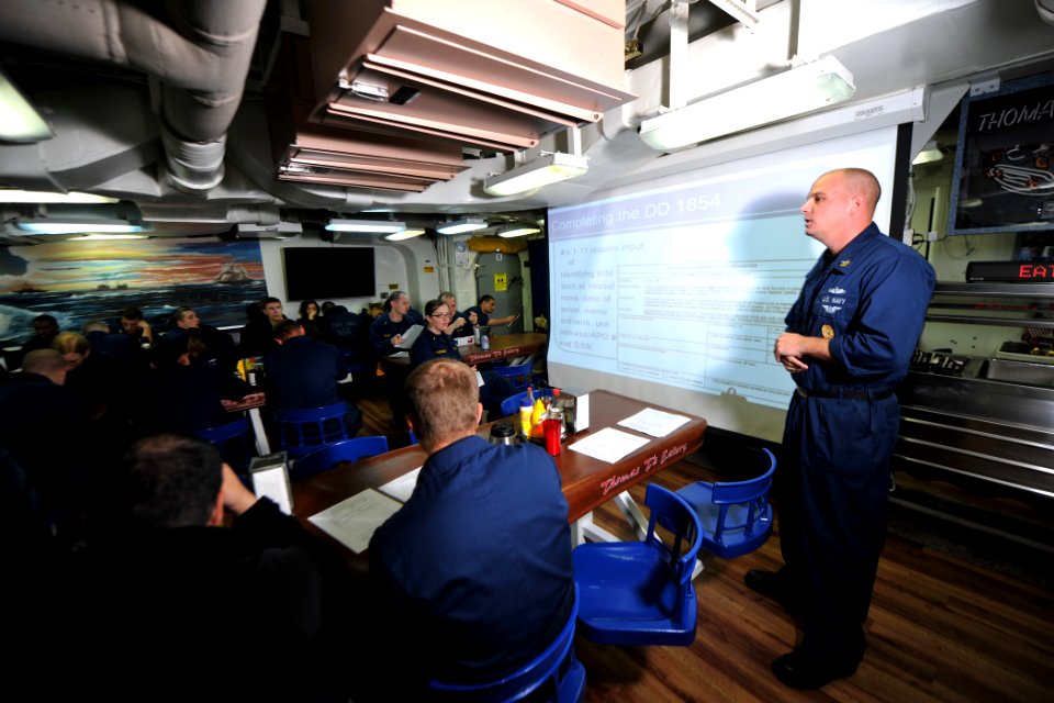 US Navy 111128-N-YZ751-037 Master-at-Arms 1st Class Matthew P. Littrel gives customs training to Sailors on the mess decks aboard the guided-missil