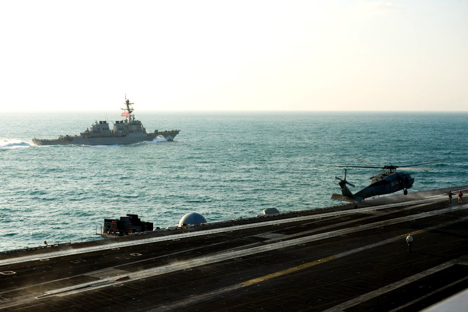 US Navy 111130-N-RJ456-029 he Arleigh Burke-class guided-missile destroyer USS Russell (DDG 59) transits alongside as an MH-60S Sea Hawk helicopter