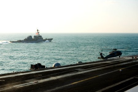 US Navy 111130-N-RJ456-029 he Arleigh Burke-class guided-missile destroyer USS Russell (DDG 59) transits alongside as an MH-60S Sea Hawk helicopter