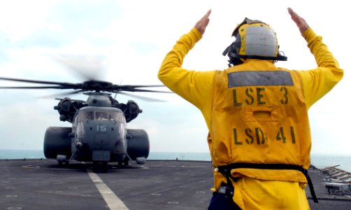 US Navy 111130-N-GH121-426 Boatswain's Mate 2nd Class Brady Laxton signals to a MH-53E helicopter from Helicopter Mine Countermeasures Squadron 15 photo