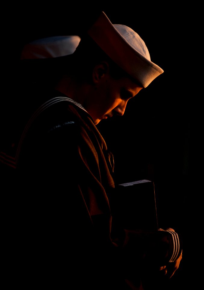US Navy 111201-N-DR144-224 Aviation Ordnanceman Airman Nathan Rings bows his head in prayer before presenting cremated remains for committal during