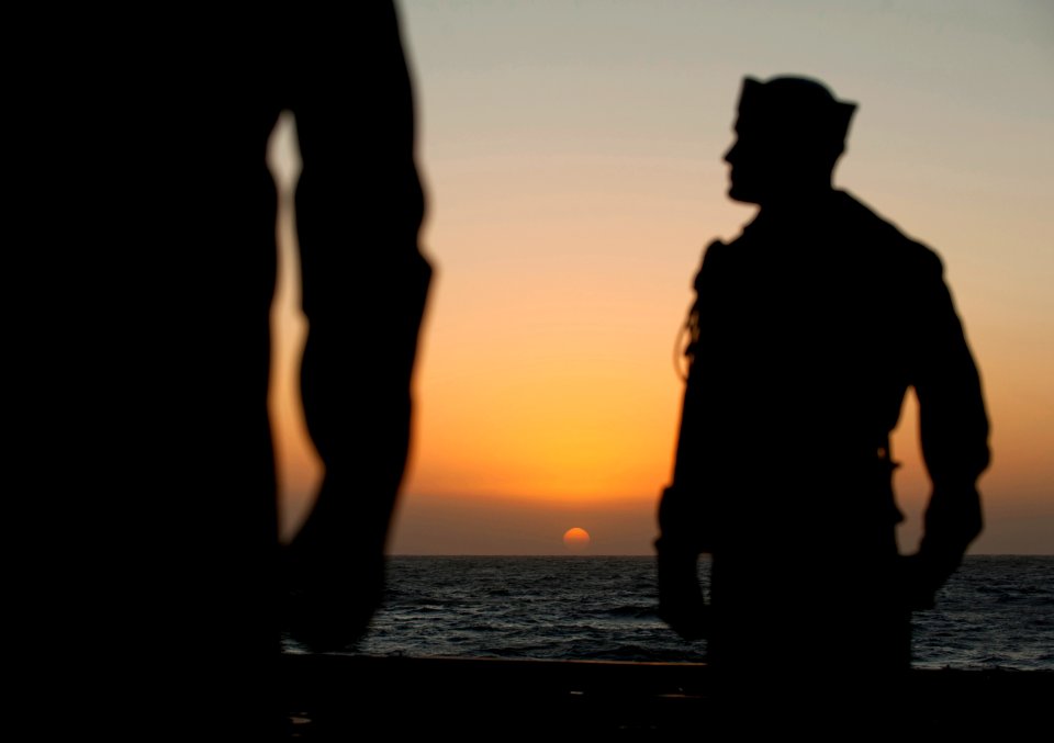US Navy 111201-N-DR144-033 The sun rises over the burial detail as they wait to begin a burial at sea ceremony for 20 former service members aboard