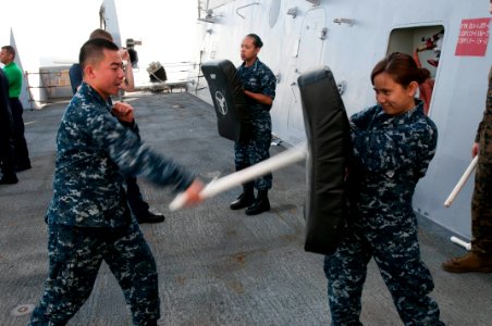 US Navy 111201-N-PB383-647 Logistics Specialist Seaman Guanglei Liu strikes a bag with a baton during a self-defense course aboard the amphibious t