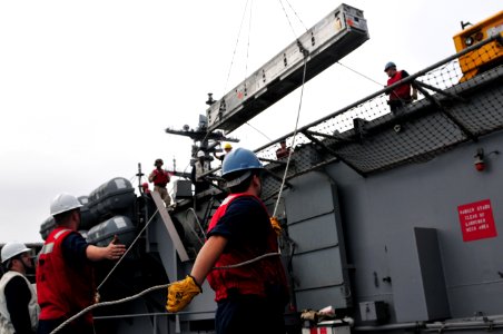 US Navy 111206-N-ZI635-162 Fire Controlman 2nd Class Paul Sannes guides a missile canister as he and other Sailors assigned to the combat systems d