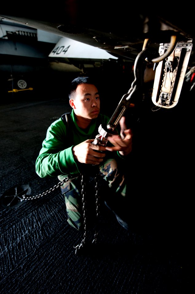 US Navy 111201-N-OY799-079 Aviation Structural Mechanic 3rd Class Tria Vang, from Lemoore, Calif., secures a tie down chain on an F-A-18C Hornet