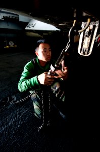 US Navy 111201-N-OY799-079 Aviation Structural Mechanic 3rd Class Tria Vang, from Lemoore, Calif., secures a tie down chain on an F-A-18C Hornet