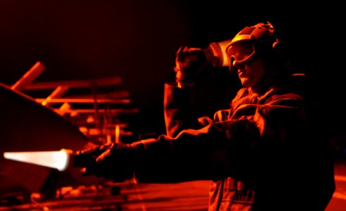 US Navy 111203-N-OY799-307 A Sailor directs an aircraft during night flight operations aboard the Nimitz-class aircraft carrier USS John C. Stennis