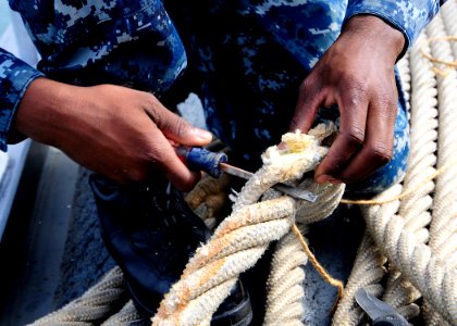 US Navy 111203-N-WJ771-066 Seaman Apprentice Luis Silva repairs a Kevlar mooring line on the forecastle of the forward-deployed amphibious dock lan