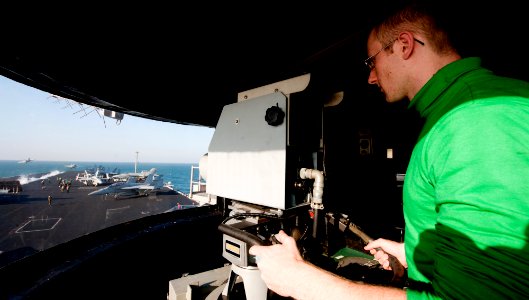 US Navy 111205-N-OY799-165 Electrician's Mate Fireman Thomas O'Hara, from Westlake, Ohio, operates the camera in the integrated launch and recovery