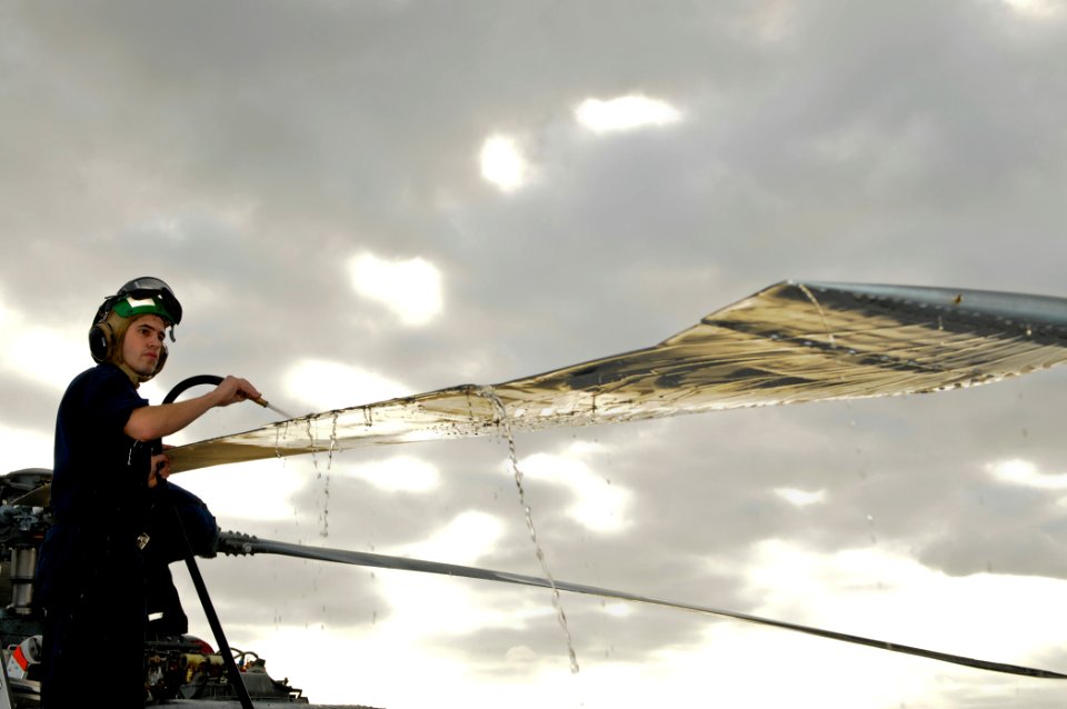 US Navy 111206-N-YM590-013 Aviation Structural Mechanic 2nd Class Kevin Barnett rinses a rotor blade of an SH-60B Sea Hawk helicopter