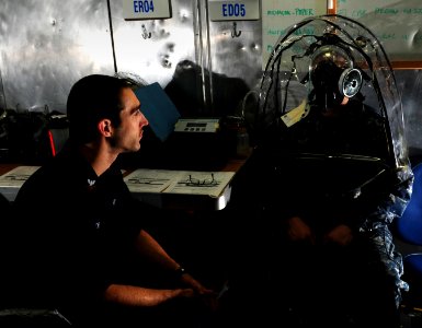 US Navy 111207-N-RG587-046 Damage Controlman 2nd Class David C. Heath instructs a Sailor wearing the joint-service mask leakage detector in a serie