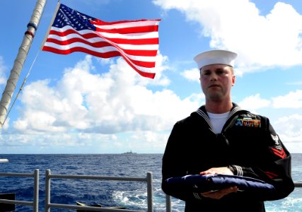US Navy 111207-N-BC134-042 Information System Technician 2nd class Nathaniel Petri carries the national ensign during a burial at sea aboard the g