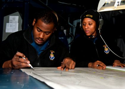 US Navy 111212-N-FI736-058 Operations Specialist 3rd Class Bryan Sherman, plots the ship's location as Operations Specialist 1st Class Teah Owens,