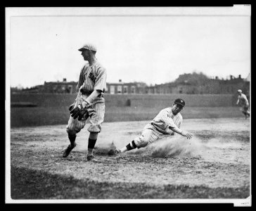 Washington Senators' Bucky Harris sliding, as he successfully steals third base in the 7th inning of a baseball game against the Boston Red Sox; third baseman Joe Dugan watches the ball roll LCCN2005676974