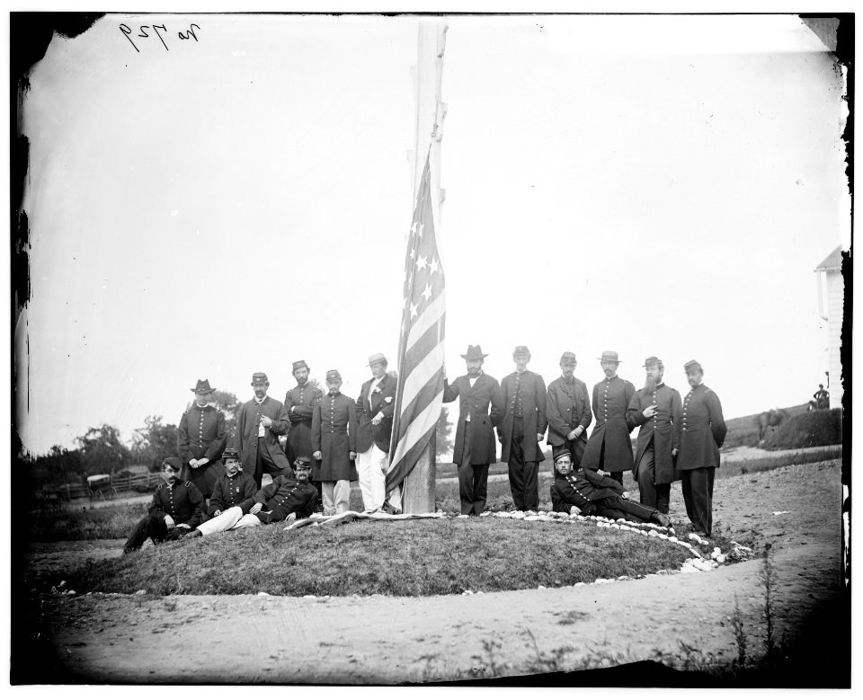 Washington, D.C. Signal Corps officers lowering flag at their camp near Georgetown; Gen Albert J. Myer, in civilian dress, at right of pole LOC cwpb.04174