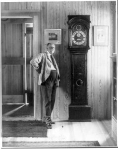 William Dean Howells, 1837-1920, full length portrait, facing right, standing by grandfather clock LCCN2005689065