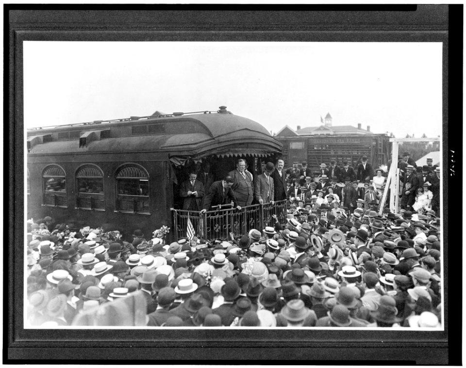 William H. Taft, full-length, standing on back of train, surrounded by crowd, during campaign tour LCCN93508104