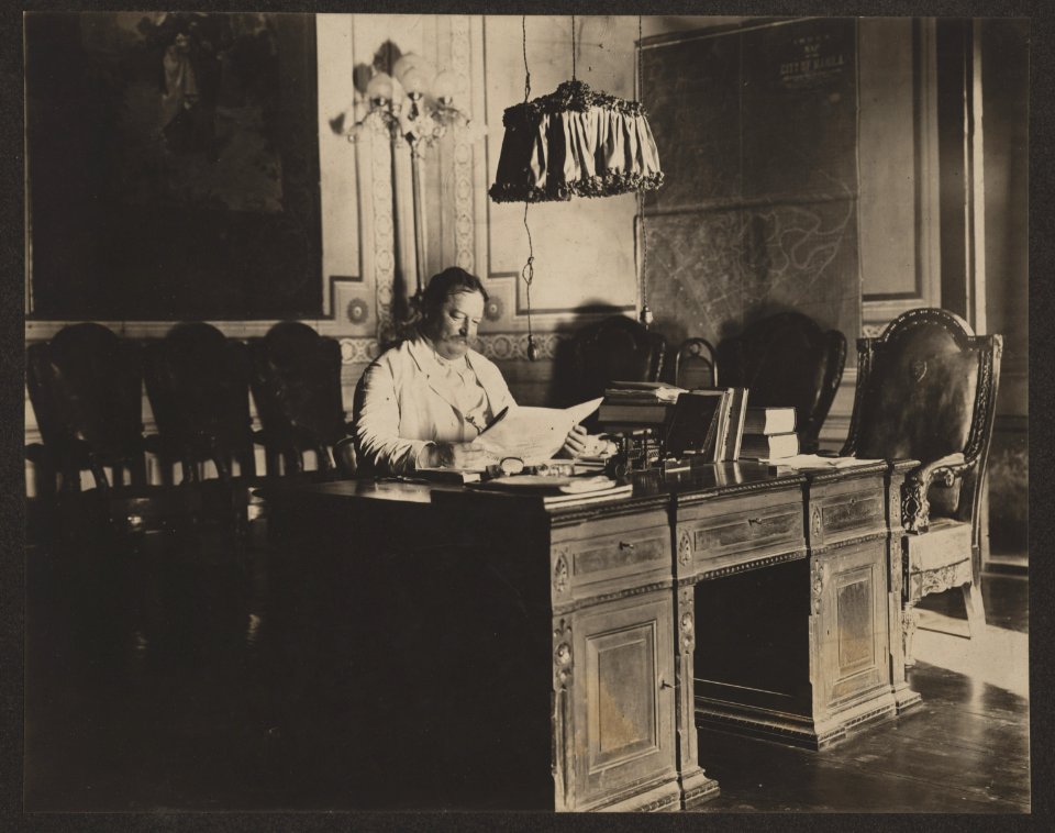 William H. Taft, Governor-General of the Philippines, seated at desk in office with map of Manila on the wall LCCN2013649078