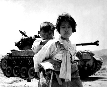 With her brother on her back a war weary Korean girl tiredly trudges by a stalled M-26 tank, at Haengju, Korea HD-SN-99-03144