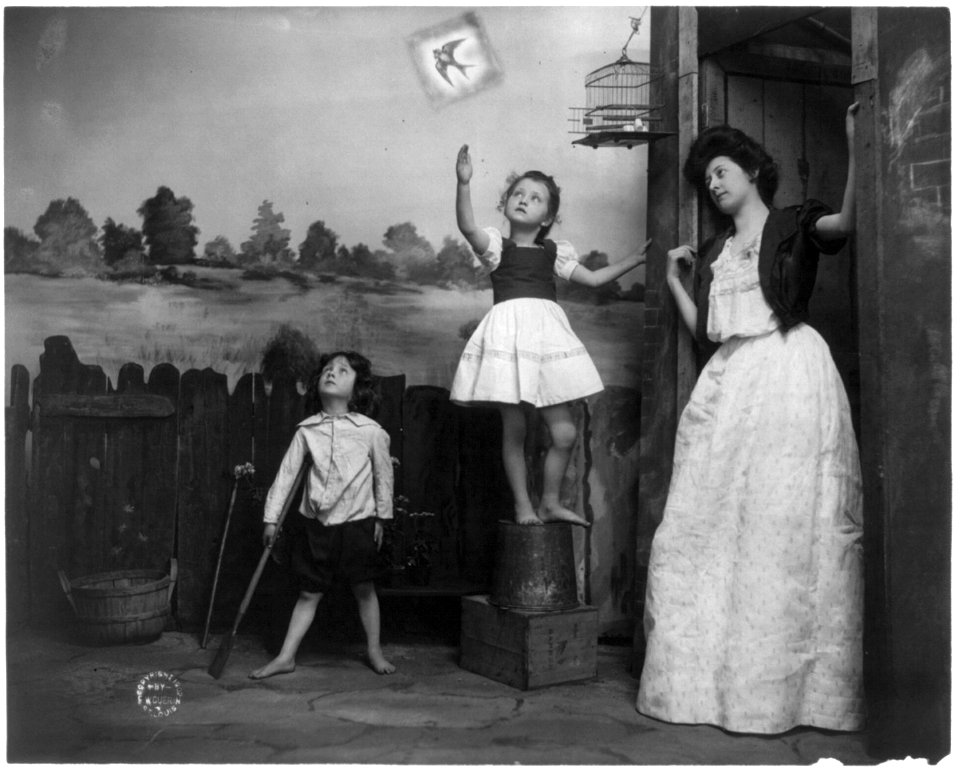Woman and 2 children watching bird fly from cage LCCN2002699165
