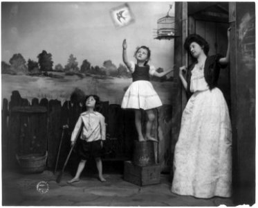 Woman and 2 children watching bird fly from cage LCCN2002699165