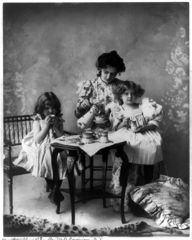 Woman and 2 girls seated at small table with cups, pitcher, etc. LCCN2002709448