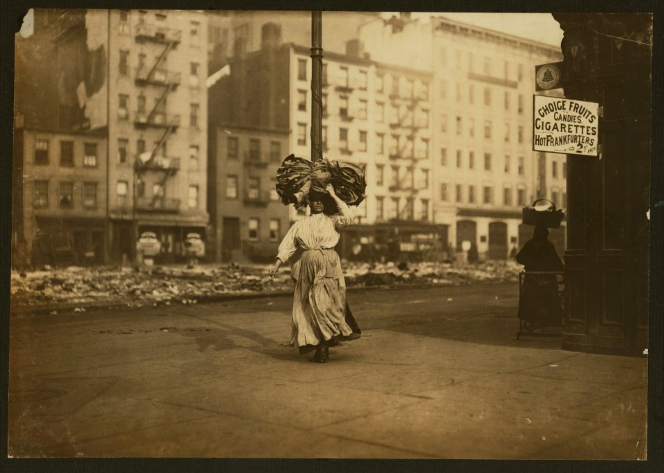 Woman carrying heavy bundle of clothing to be finished at home. Near Astor Place, N.Y. LOC cph.3a27627