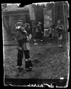 Woman carrying a child crossing a street, Chinatown, San Francisco LOC agc.7a09025
