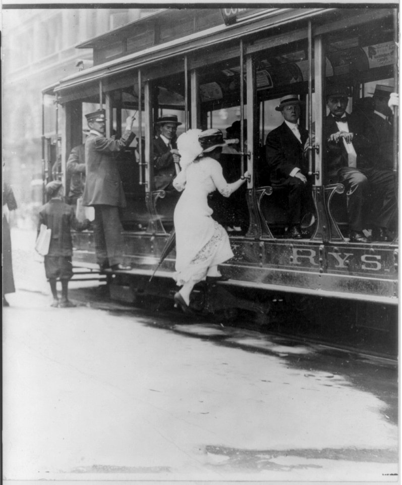 Woman boarding NYC streetcar by jumping onto running board. 1913 LCCN2006690173