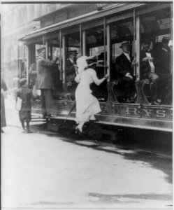 Woman boarding NYC streetcar by jumping onto running board. 1913 LCCN2006690173