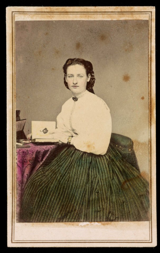 Woman in green colored skirt, seated at table with photo album) - J. G. Stacy, Dover, Me LCCN2016653151