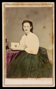 Woman in green colored skirt, seated at table with photo album) - J. G. Stacy, Dover, Me LCCN2016653151