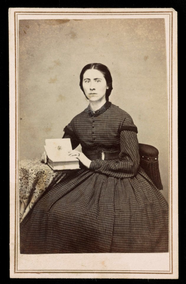 Woman in checkered dress, seated at table with photo album) - J. G. Stacy, Dover, Me LCCN2016653159
