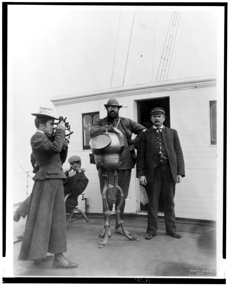 Woman looking through sextant on board the expedition vessel, George W. Elder, with two men and Capt. Peter Doran during Harriman expedition to Alaska, 1899) - Curtis LCCN2002706858
