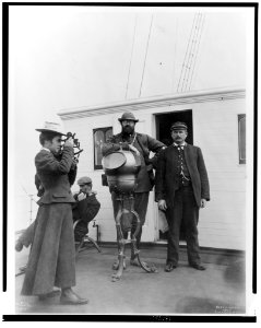 Woman looking through sextant on board the expedition vessel, George W. Elder, with two men and Capt. Peter Doran during Harriman expedition to Alaska, 1899) - Curtis LCCN2002706858