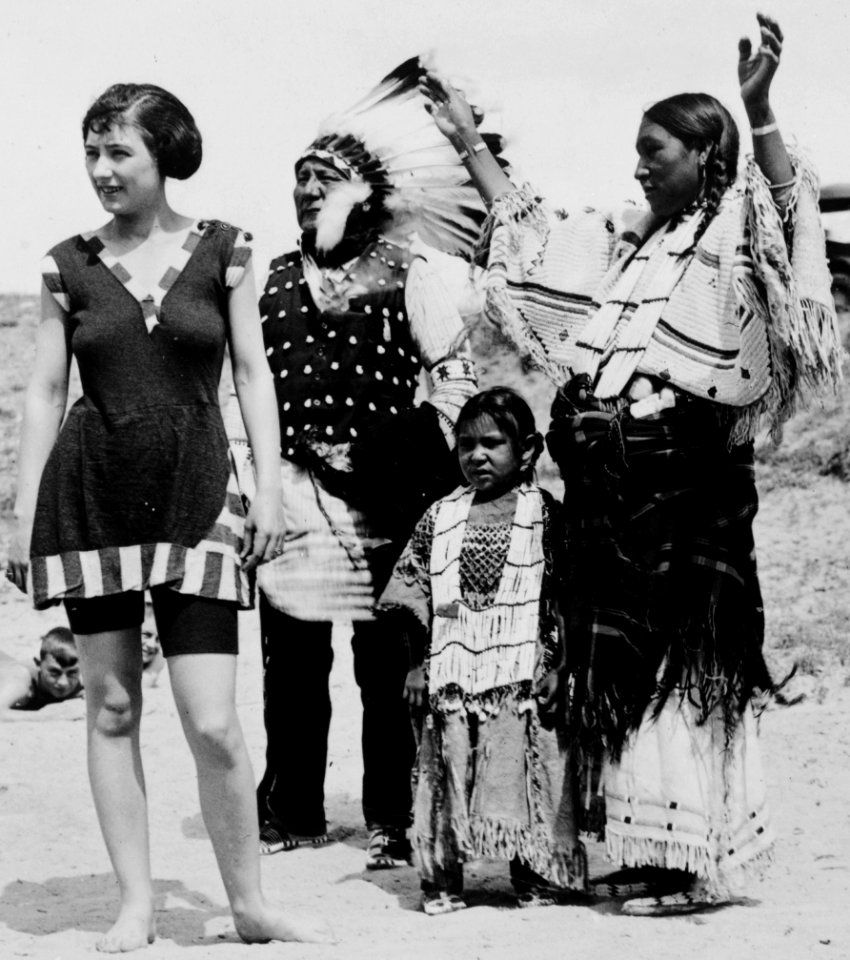 Woman in swimsuit on beach with an Indian family in 1923- LCCN99471588 (cropped)
