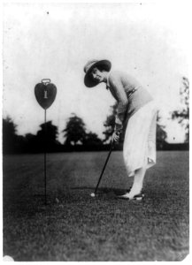 Woman swinging at golf ball close to hole, Washington, D.C., area LCCN89708771
