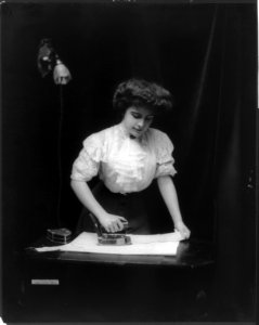 Woman using electric iron plugged into light socket LCCN2006686991