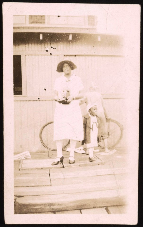 Woman, holding camera, standing on steps with a child LCCN2015650136