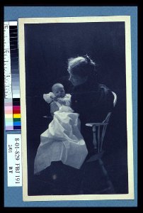 Woman, sitting in chair, holding an infant, full-length portrait LCCN2004676319 photo