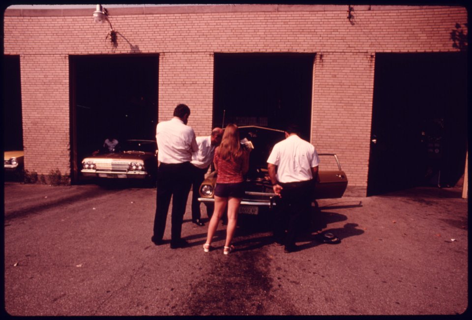 Woman, Center, Is Having Minor Adjustments Made to Her Auto's Carburetor During Retesting after Her Vehicle Had Failed at an Auto Emission Inspection Station in Downtown Cincinnati, Ohio...09-1975 (4265796349)