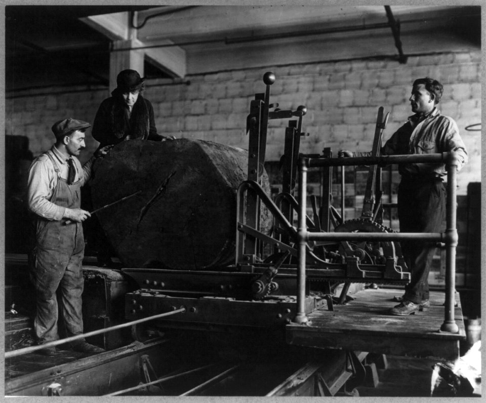 Wooden box industry - Mrs. Graham inspecting log on machinery with two workmen standing by LCCN2003654896